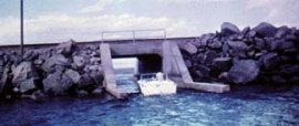 A power boat takes advantage of the low water to pass through the rail road causeway.